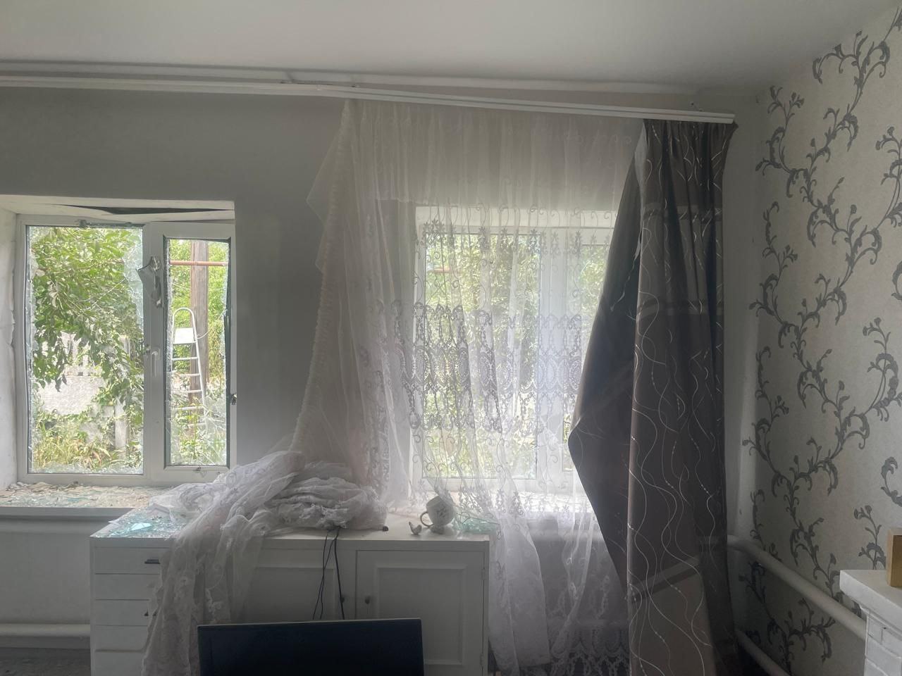 Кімната в будинку після ворожої атаки: розбиті вікна, обірвані штори