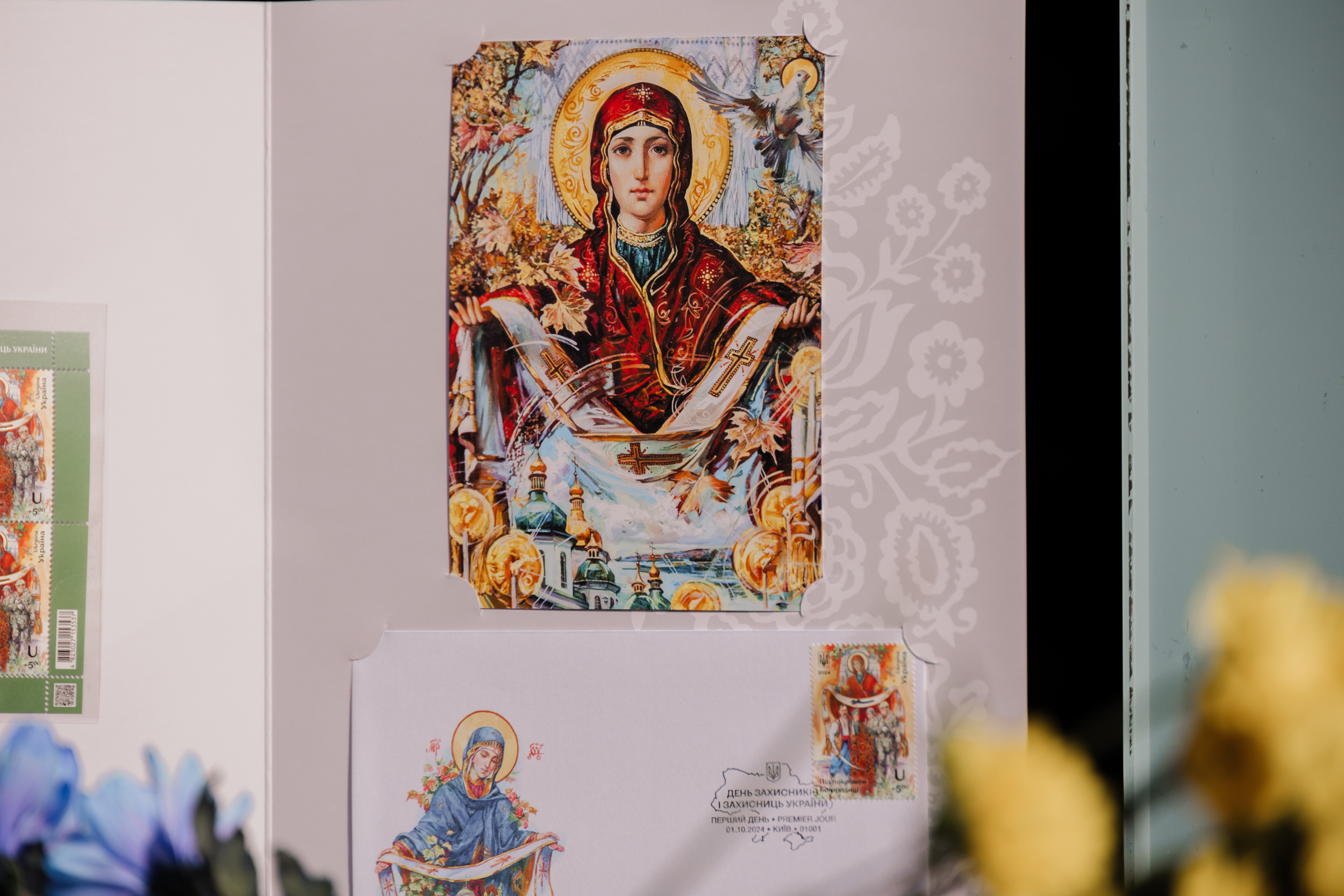 На марці зображена Діва Марія, яка наче оберігає воїнів.