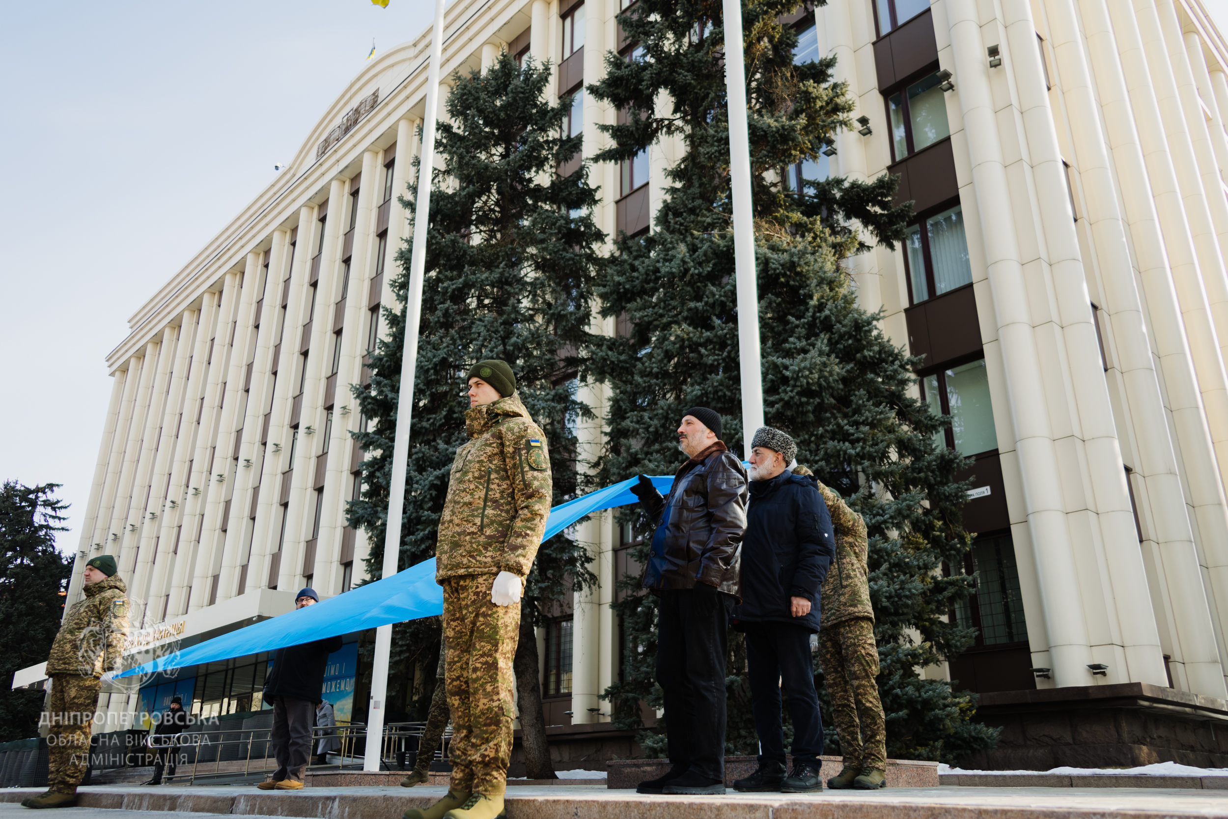 Блакитне полотнище із жовтим гербом тримають, поки лунає гімн
