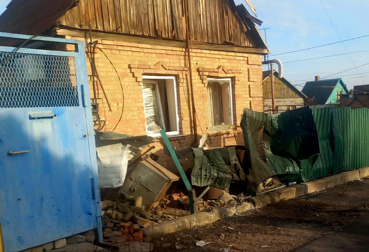 Понівечені будинок та паркан поряд 