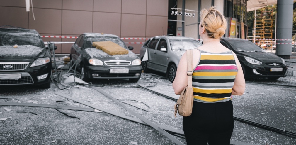 Мешканка Дніпра оглядає понівечені автівки після ворожої атаки