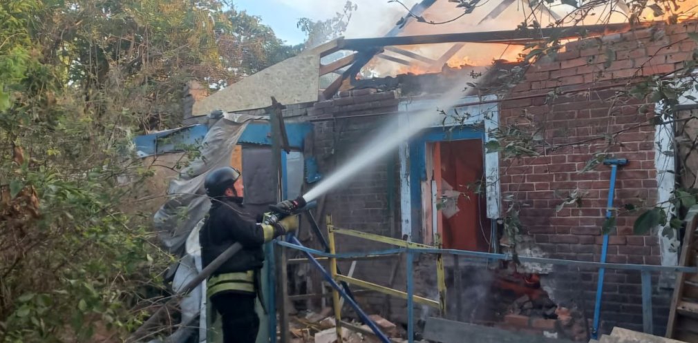 Рятувальник приборкує пожежу в будинку, яка сталася через ворожу атаку