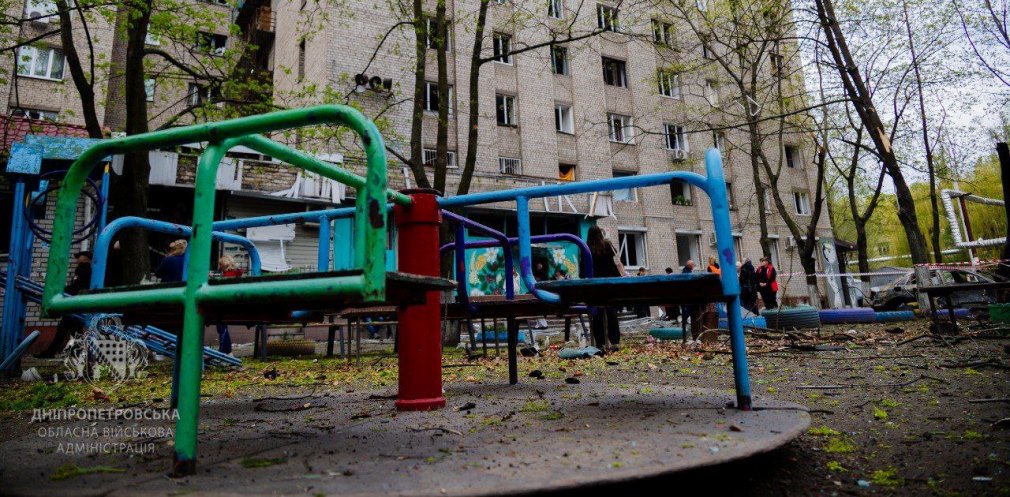 Дитячий майданчик поряд з понівеченою багатоповерхівкою