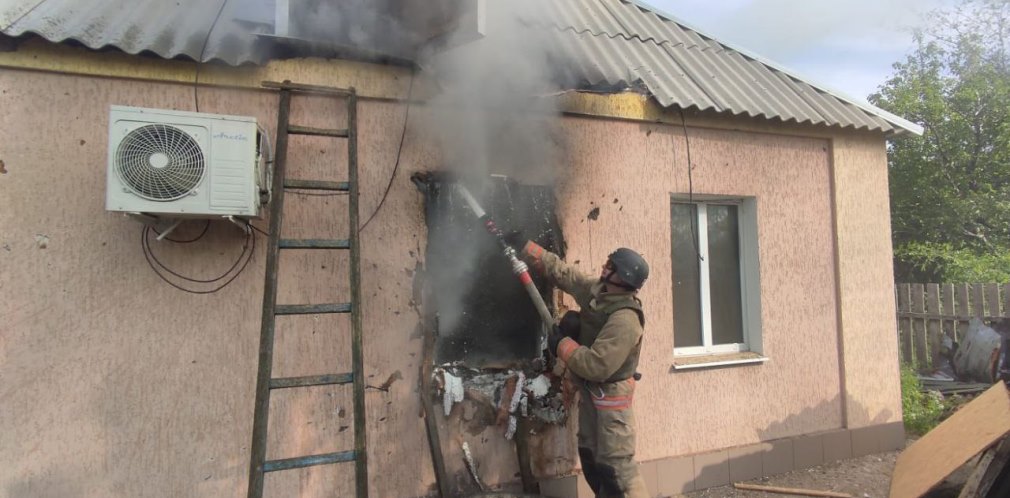 Рятувальник приборкує пожежу в приватному будинку, який зайнявся через російську атаку